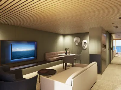 Wohnbereich einer luxuriösen Suite der Norwegian Luna mit großem TV, Essgruppe und Sofas. Moderne Einrichtung mit Holzdecke und indirektem Licht.