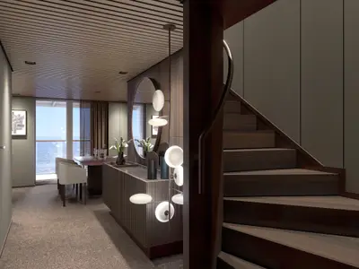 Luxuriöse Duplex-Suite der Norwegian Luna mit Esstisch am Meerblick-Fenster, moderner Pendelleuchte und eleganter Holztreppe. Stilvolles, offenes Design.