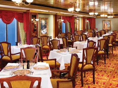 Luxuriöses Le Bistro Spezialitätenrestaurant an Bord der Norwegian Pearl. Gedeckte Tische, elegante Holzstühle mit goldenen Bezügen, rote Vorhänge und Kronleuchter prägen das Ambiente.