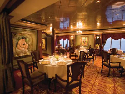 Innenansicht des eleganten Spezialitätenrestaurants Le Bistro an Bord der Norwegian Pearl. Mehrere Tische sind fein eingedeckt, Gemälde zieren die Wände und große Fenster bieten Meerblick.