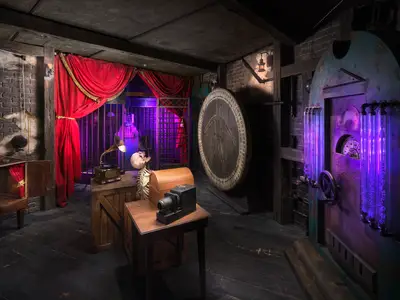 Der detailreiche Escape Room an Bord der Norwegian Prima. Rote Vorhänge, ein Skelett, ein Grammophon und violette Leuchtröhren schaffen eine geheimnisvolle und rätselhafte Atmosphäre.