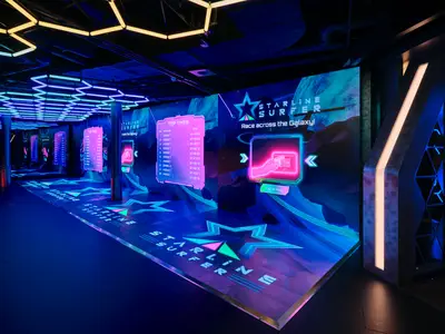 Der Starline Surfer Gaming-Bereich an Bord der Norwegian Prima, beleuchtet mit Neonlichtern und interaktiven Bildschirmen. Spieler können ihre Zeiten auf Anzeigetafeln sehen.