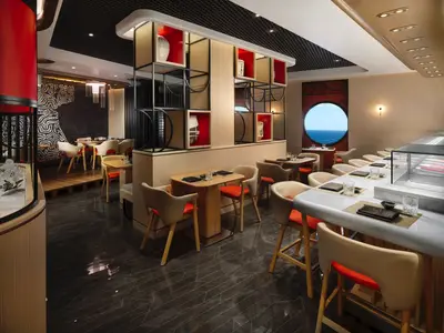 Innenansicht des modernen Nama Sushi Restaurants an Bord der Norwegian Prima mit elegantem Design, Holzakzenten und Bullaugenfenster zum Meer. Eine Sushi-Theke und mehrere Tische sind zu sehen.