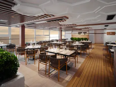 Blick in das moderne Palomar Spezialitätenrestaurant an Bord der Norwegian Prima. Elegante Tische sind gedeckt, dahinter bieten Panoramafenster einen weiten Meerblick bei Sonnenuntergang.