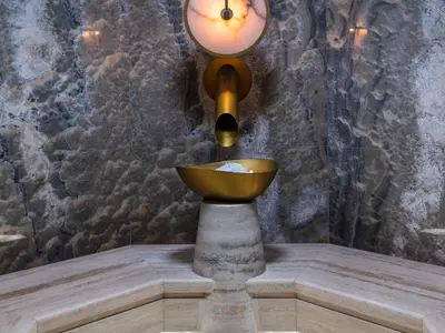 Ein luxuriöser Eisbrunnen im Spa-Bereich der Norwegian Prima. Goldener Spender gibt Eis in eine goldene Schale, umgeben von elegantem Marmor.