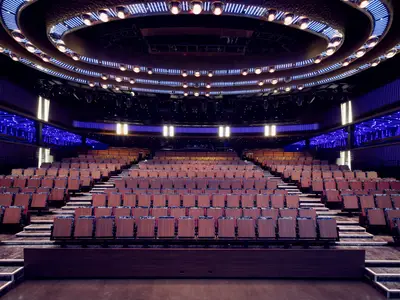 Das moderne Theater an Bord der Norwegian Prima. Leere Sitzreihen, futuristische Beleuchtung mit blauen LEDs und goldenen Spots an Decke und Wänden schaffen eine einzigartige Atmosphäre für Abendshows und Unterhaltung.