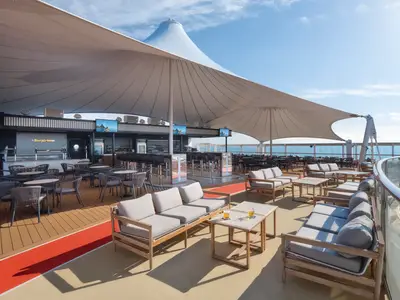 Panoramablick auf die offene Biergärten Bar-Lounge auf dem Sonnendeck der Norwegian Spirit, mit verschiedenen Sitzbereichen, Sonnensegeln und Meerblick.
