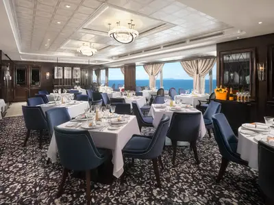 Elegantes Restaurant Le Bistro an Bord der Norwegian Spirit. Blaue Samtstühle und weiß gedeckte Tische laden zum Verweilen ein. Große Fenster bieten einen malerischen Blick auf das weite Meer.