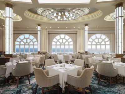 Ein elegantes, lichtdurchflutetes Restaurant an Bord der Norwegian Spirit mit zahlreichen Tischen und bequemen Stuehlen. Grosse, bogenfoermige Fenster bieten einen weiten Blick auf das offene Meer.