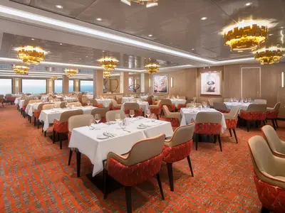 Der helle Speisesaal Taste an Bord der Norwegian Spirit bietet viele gedeckte Tische und bequeme Stühle. Große Fenster mit Meerblick und moderne goldene Kronleuchter kennzeichnen den eleganten Raum. Ohne Personen.