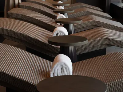 Eine Reihe bequemer, ergonomischer Thermal-Liegen mit gewebter Oberfläche und aufgerollten weissen Handtüchern an Bord der Norwegian Spirit.