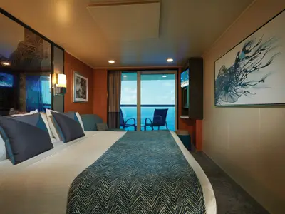 Moderne Balkonkabine an Bord der Norwegian Star mit bequemem Bett und blauen Akzenten. Eine Glastür führt zu einem Balkon mit weitem Meerblick.