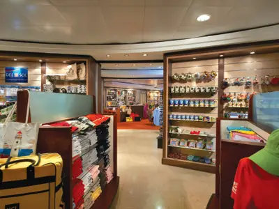Blick in den Shop Trade Routes an Bord der Norwegian Star. Zahlreiche Regale mit Souvenirs, Kleidung und Taschen. Helle Beleuchtung.