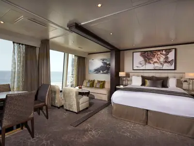 Geräumige Suite der Norwegian Star mit Meerblick. Links Essbereich, mittig Wohnbereich mit Sofa, rechts Schlafzimmer mit Doppelbett. Elegante Einrichtung.