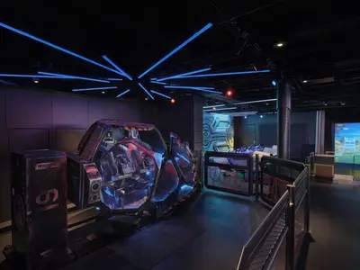 Blick auf das dunkle, futuristisch gestaltete Galaxy Pavilion an Bord der Norwegian Viva mit leuchtenden VR-Simulatoren und blauen Neonröhren an der Decke. Rechts ein Golfsimulator.