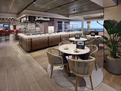 Innenansicht der modernen Dessert-Bar 'Just Desserts' an Bord der Norwegian Viva mit Theke, reichhaltiger Dessertauslage, eleganten Sitzbereichen und großem Meerblickfenster.