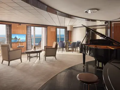 Geräumiges Wohnzimmer einer Deluxe Owner's Suite an Bord der Pride of America mit elegantem Grand Piano, Essbereich, TV und Zugang zum Balkon mit Meerblick.