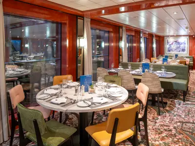 Das moderne Restaurant des Flusskreuzfahrtschiffs Belvedere. Gedeckte Tische, bunte Stühle, grüne Bänke, Fenster und Wandkunst. Einladendes Ambiente.