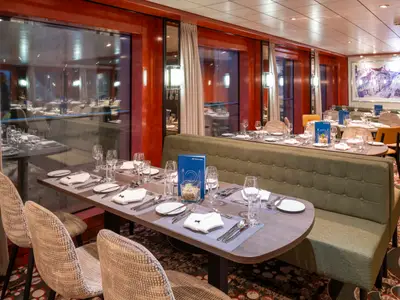 Blick ins Restaurant der Belvedere: Gedeckte Tische, grüne Sitzbänke und Stühle. Große Fenster und ein Wandgemälde prägen den stilvollen Raum auf dem Schiff.