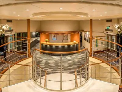Moderne Lobby der Bijou du Rhône mit zentraler Rezeption, umgeben von zwei eleganten Treppen mit Holzgeländern und Metallstreben.
