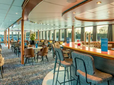 Der Barbereich der Bijou du Rhône: eine lange Theke mit Barhockern, diverse Sitzgruppen und große Fenster mit Blick auf die Flusslandschaft.