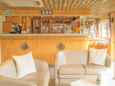 Bar- und Loungebereich der La Belle de Cadix mit hellen Ledersitzmöbeln, einer Holztheke mit Getränken und einem Fensterblick.