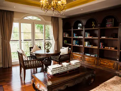 Blick in die elegante Bibliothek des Flusskreuzfahrtschiffs Mekong Navigator. Dunkle Holzregale, ein Schiffsmodell auf dem Couchtisch und große Fenster sind sichtbar.