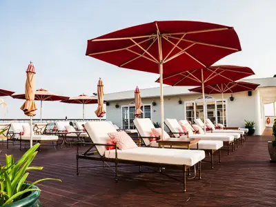 Das Sonnendeck des Mekong Navigator mit Liegen, roten Sonnenschirmen und Holzplanken. Im Hintergrund ein weißes Schiffsgebäude.