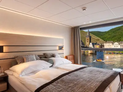 Helle Außenkabine mit Flussblick auf malerisches Dorf, Brücke und grüne Weinberge.
