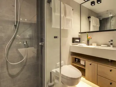 Modernes Badezimmer mit begehbarer Dusche, Waschtisch und Toilette in einer hellen Ausstattung.