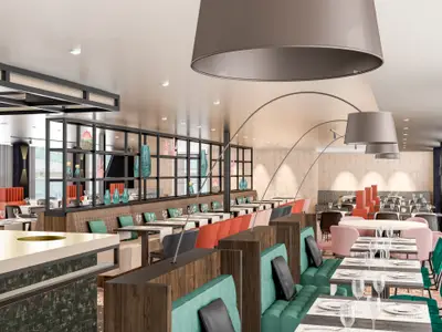 Das elegante Restaurant der nickoSPIRIT zeigt helle Speisebereiche, farbige Sitzbänke und Tische. Im Hintergrund eine Fensterfront mit Blick aufs Wasser. Große Pendelleuchten schmücken die Decke.