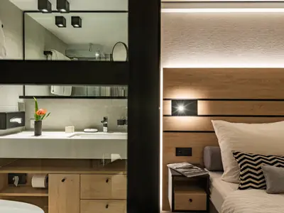 Moderne Suite mit Schlafbereich und Bad. Helle Holzmöbel und indirekte Beleuchtung.