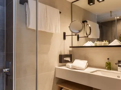 Helles, modernes Badezimmer in einer Kabine mit Dusche, Waschbecken und Pflegeprodukten.