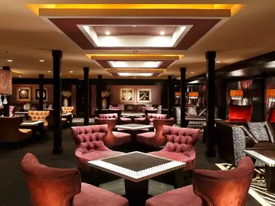 Innenansicht der schicken Lounge an Bord des Flusskreuzfahrtschiffs Steigenberger Omar El Khayam. Plüschige Sessel, dunkle Hölzer und warme Beleuchtung schaffen eine einladende Atmosphäre.