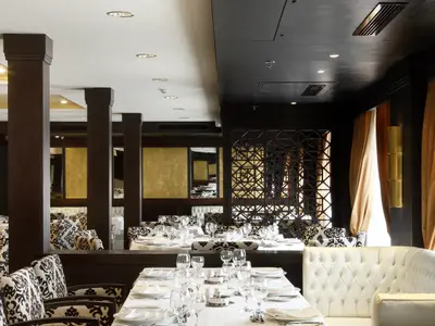Innenansicht des Speisesaals auf der Steigenberger Omar El Khayam. Elegant gedeckte Tische mit weißen Tischdecken, Gläsern und Stühlen. Dunkle Säulen und eine dekorative Trennwand.