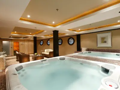 Wellnessbereich der Steigenberger Omar El Khayam mit zwei Whirlpools. Dahinter sind eine Lounge mit Sitzmöbeln, runde Bullaugen mit Ausblick und eine Sauna sichtbar.