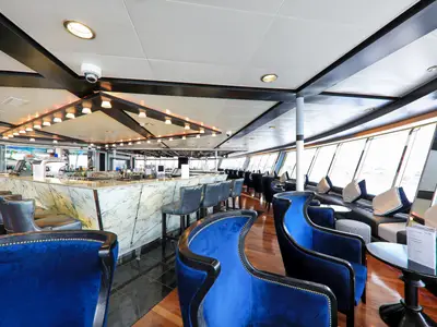 Blick in die elegante Lounge-Bar der Vasco da Gama. Eine geschwungene Marmortheke, bequeme blaue Samtsessel und große Fenster mit Ausblick auf das Wasser prägen den Raum.