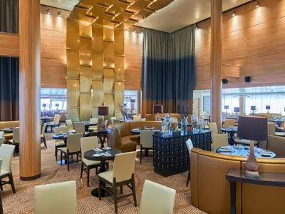 Das elegante Restaurant der Vasco da Gama zeigt Tische, Stühle, Ledersitzbänke, Holzvertäfelung und goldene Wanddekoration. Große Fenster prägen den Raum.