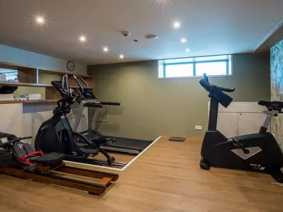 Moderner Fitnessraum an Bord der MS Adora. Ausstattung: Ergometer, Laufband, Rudergerät. Helle Wände und Boden, Fenster. Handtücher liegen bereit.