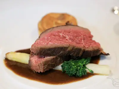 An Bord der MS Alena: Ein Teller mit rosa Rinderfilet, brauner Sauce, Spargel und Brokkoli. Unscharf im Hintergrund ein Yorkshire Pudding.