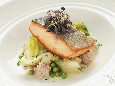 Knuspriges Lachsfilet mit Microgreens, angerichtet auf Erbsen, Schalotten und Salatherzen auf weißem Teller an Bord der MS Alisa.