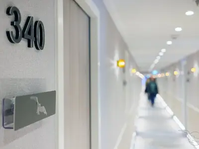 Nahaufnahme einer Kabinentür mit der Nummer 340 und einem Schild am Kabinenkorridor an Bord der MS Amina. Im Hintergrund verschwimmt ein heller Gang mit Beleuchtung und einer Person.