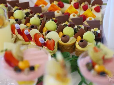 Nahaufnahme einer Auswahl kunstvoll arrangierter Desserts an Bord der MS Amina, darunter Erdbeer-Törtchen, Limetten-Mousse und Schokoladenpralinen.