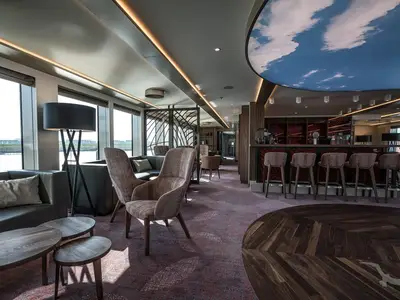 Blick in die stilvolle Bar-Lounge der MS Andrea mit großen Fenstern, bequemen Sesseln, Bar und Himmelsdecke.