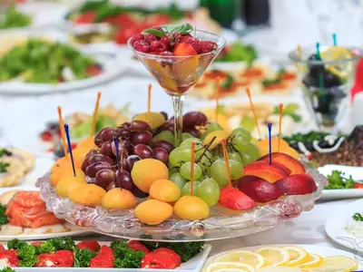 Ein großes Glas mit Himbeeren und Pfirsichen auf einem Buffet der MS Anesha. Ein Obstteller mit Trauben, Aprikosen und Pfirsichen ist davor angerichtet.