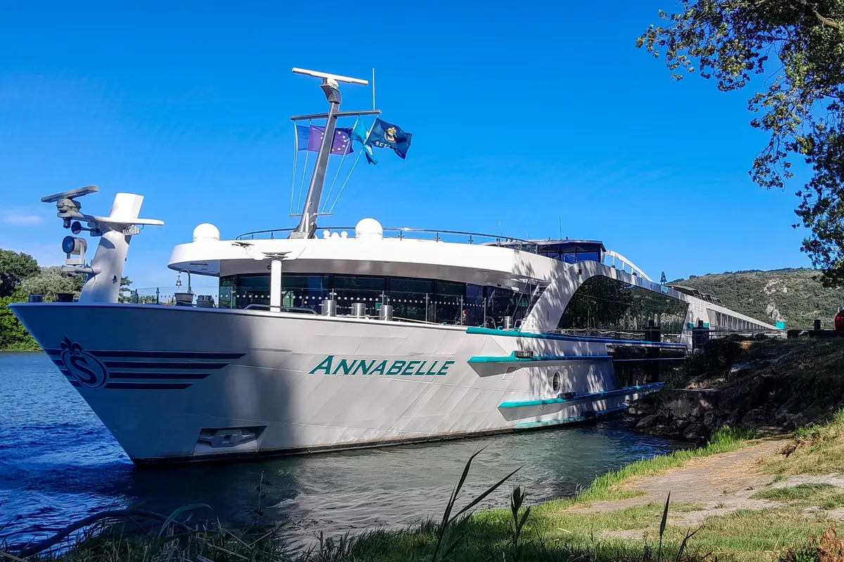 Die MS Annabelle liegt an einem sonnigen Tag am grünen Flussufer der Rhône, mit blauem Himmel im Hintergrund.