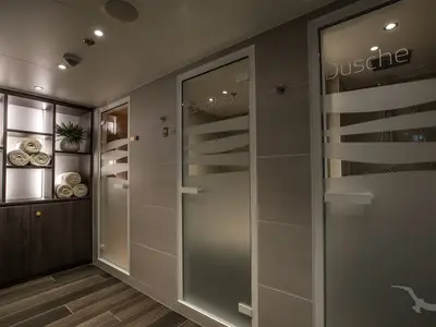 Moderner Spa-Bereich an Bord der MS Annabelle. Regale mit gerollten Handtüchern und einer Pflanze. Zwei Milchglastüren führen zu einem Dampfbad und einer Dusche.