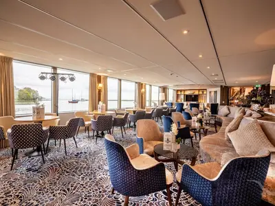 Die helle Bar-Lounge an Bord der MS Annika bietet bequeme Sitzgelegenheiten und große Fenster mit Panoramablick auf Fluss und Ufer.