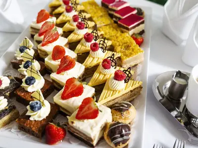 Eine verlockende Auswahl an kleinen Kuchen und Tortenstücken, dekoriert mit frischen Früchten, an Bord der MS Annika. Rechts eine Kaffeetasse und Milchkännchen.