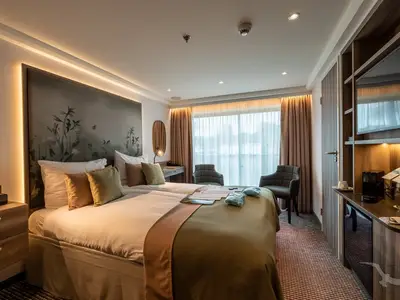 Helle Balkonkabine der MS Antonia. Modernes Design mit Doppelbett, Schreibtisch, Sessel und großen Panoramafenstern. Florales Wandbild und indirekte Beleuchtung.